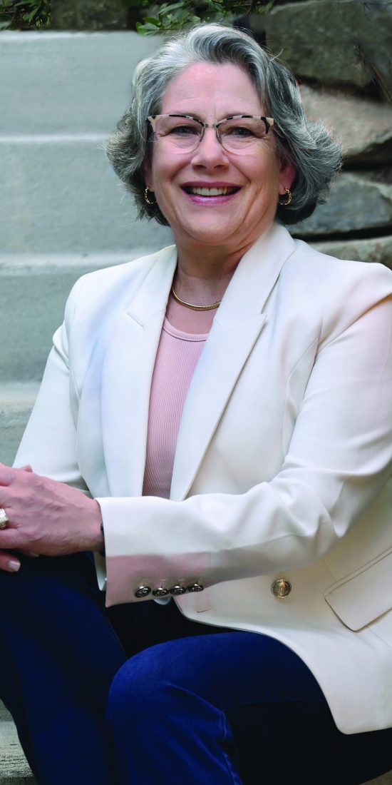 Photo of Molly Erin McCabe Sitting on steps in off white jacket and pink shell top.